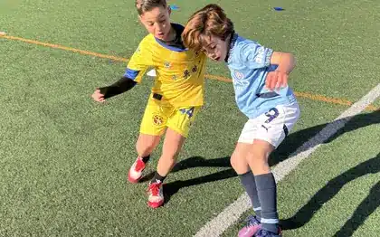 Dos niños disputando el balón en un clinic intensivo de INTTACTIC